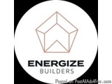 The image is a logo for Energize Builders. It is a white circle with a rose gold line drawing of a cube in the center. The cu...