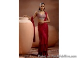 The image shows a young woman wearing a traditional Indian saree. She is standing in front of a large terracotta pot and is p...