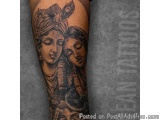 The image is a tattoo on someone's arm. It is a black and grey tattoo of two Hindu deities, Krishna and Radha, facing each ot...