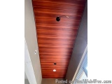 The image shows a wooden door with vertical slats on it. The door appears to be in a room with a beige wall on the left side...