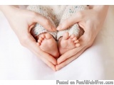 The image shows a pair of hands holding a baby's feet in the shape of a heart. The hands are gently cradling the feet, with t...