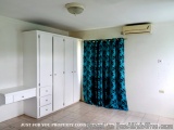 The image shows a room with a white wardrobe and a blue curtain. The wardrobe has six doors and six drawers, and there is a w...