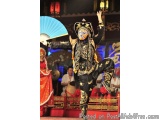 The image shows a person performing a traditional Chinese dance. The person is wearing a black and gold costume with intricat...