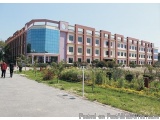 The image shows a large, multi-storey building with a modern design. The building has a pink and white color scheme with a cu...