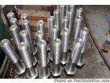 The image shows a group of cylindrical metal objects, which appear to be made of steel or aluminum, stacked on top of each ot...