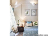 The image shows a bedroom with a modern and minimalistic design. The walls are painted in a light beige color and the floor i...