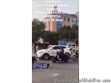 The image shows a street scene in Janakpur, India. There are several vehicles on the road, including a white car and a black...
