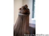 The image shows the back of a woman's head with long, straight hair. The hair is styled in a messy bun with a black hair clip...