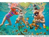 The image shows a group of three people snorkeling in the ocean. The person on the left is wearing a colorful striped swimsui...