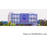 The image shows a large, modern building with a blue and white color scheme. The building appears to be a school or a college...