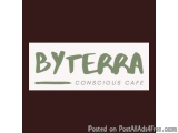 The image is a logo for a cafe named "BYTERRA". The logo is written in a modern, sans-serif font and is in a light green colo...