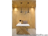 The image shows a modern office space with a wooden wall on the left side and a white desk on the right side. The desk has a...