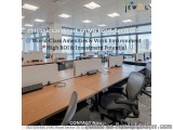 The image shows an office space with multiple desks and chairs arranged in rows. The desks are made of wood and have computer...