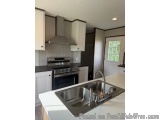 This image shows a modern kitchen with white cabinets and a stainless steel sink. The kitchen has a large island with a doubl...