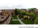 The image shows an aerial view of a beautiful courtyard with a well-manicured lawn and a stone pathway. The courtyard is surr...