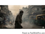 The image shows a man wearing a face mask walking on a street in an urban area. The street is filled with vehicles and people...