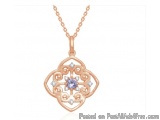 The image is of a rose gold pendant necklace. The pendant is in the shape of a flower with a central blue sapphire in the cen...