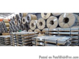 The image shows a large warehouse filled with stacks of steel coils. The coils are arranged in a neat and orderly manner, wit...