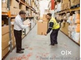 The image shows two men in a warehouse, both wearing high visibility vests. They are standing in front of a large warehouse a...