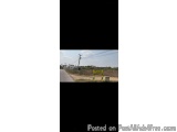 The image is a photograph of a rural area. The photograph is taken from a low angle, looking up at the sky. The sky is blue a...