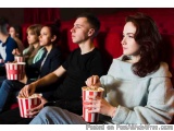 The image shows a group of people sitting in a movie theater, watching a movie. They are all holding red and white striped po...