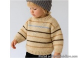 The image shows a young child, probably around 2-3 years old, wearing a knitted sweater and a beanie. The sweater is beige wi...