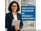 The image shows a young woman in a business suit holding a laptop and smiling at the camera. She is standing in front of a mo...