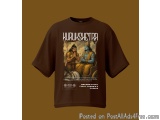 The image is of a brown t-shirt with a graphic design on the front. The design features two figures, one sitting on a throne...
