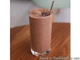 The image shows a tall glass filled with a smoothie. The smoothie appears to be a rich, chocolatey color and is topped with a...