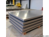The image shows a stack of steel plates in a warehouse. The plates are arranged in a horizontal manner and are stacked on top...
