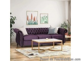 The image shows a modern living room with a purple velvet sofa in the center. The sofa has a tufted design with a buttoned ba...