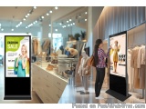 The image shows a clothing store with two large digital signage boards on the right side of the image. The boards are display...