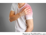 The image shows a person from the waist down, wearing a white t-shirt. The person is holding their shoulder in pain, with the...