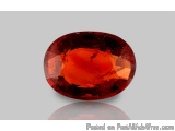 The image is a close-up of a large, oval-shaped gemstone. The gemstone appears to be a deep red color with a smooth, polished...