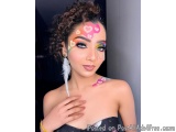 The image is a close-up portrait of a young woman with a unique and creative makeup look. She has dark hair styled in a messy...
