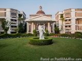 The image shows a beautiful garden with a fountain in the center. The fountain is made of white marble and is surrounded by a...