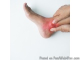 The image shows a person's foot with a red spot on it. The person's hand is gently touching the foot, with their index finger...
