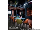 The image shows the interior of a restaurant named NYSA. The restaurant has a modern and industrial design with a high ceilin...