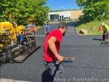 The image shows a group of construction workers working on a road. There are four men in the image, two of whom are wearing r...