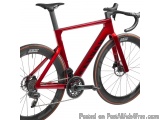 The image is of a red and black road bike. The bike has a sleek design with a black saddle and handlebars. The frame is made...
